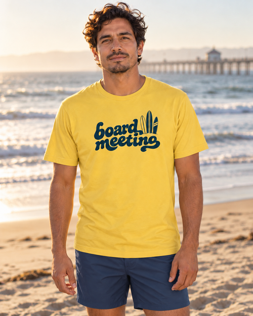 Yellow Board Meeting Tee worn with navy swim trunks at the shoreline