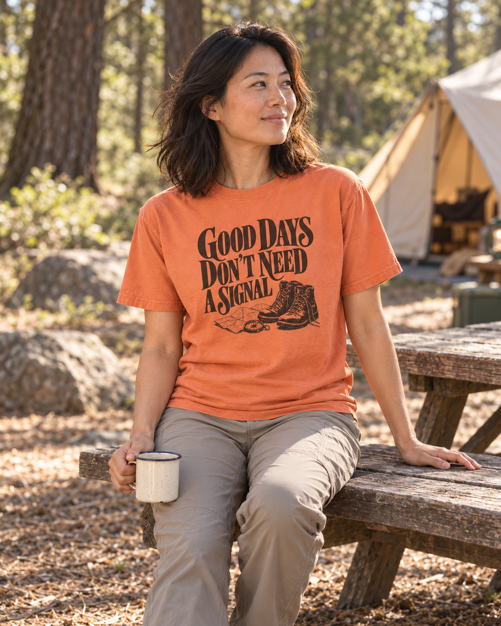 Good Days Don't Need a Signal Tee — Terracotta — lifestyle seated with coffee at a woodland campsite