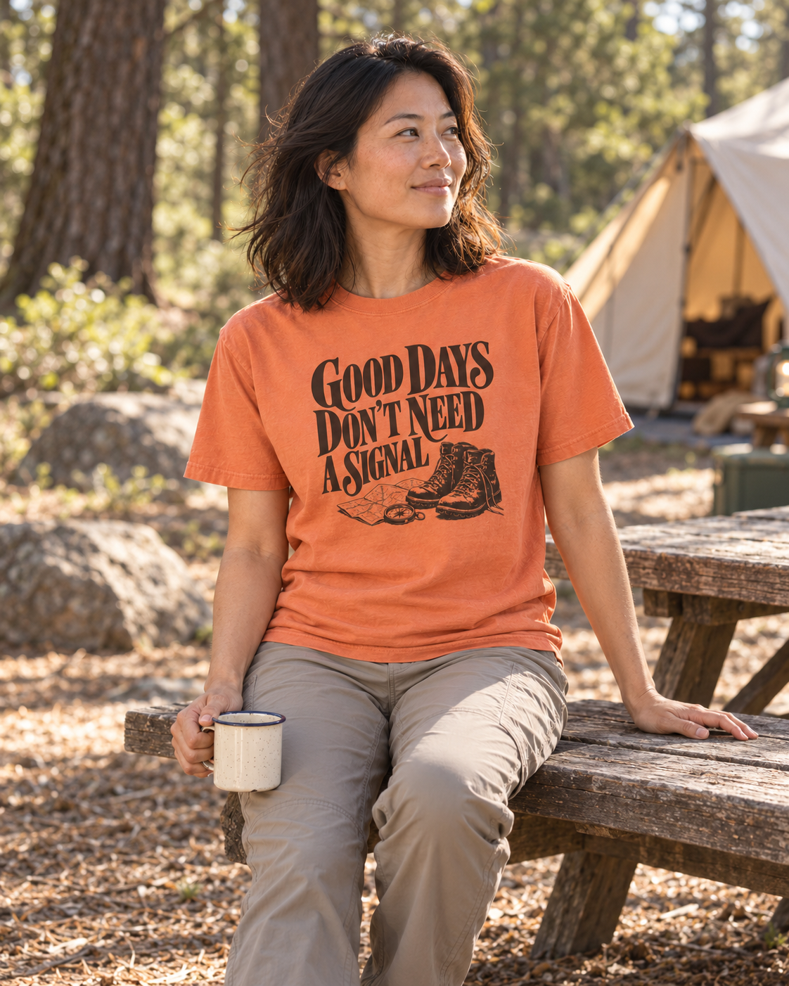 Good Days Don't Need a Signal Tee — Terracotta — lifestyle seated with coffee at a woodland campsite
