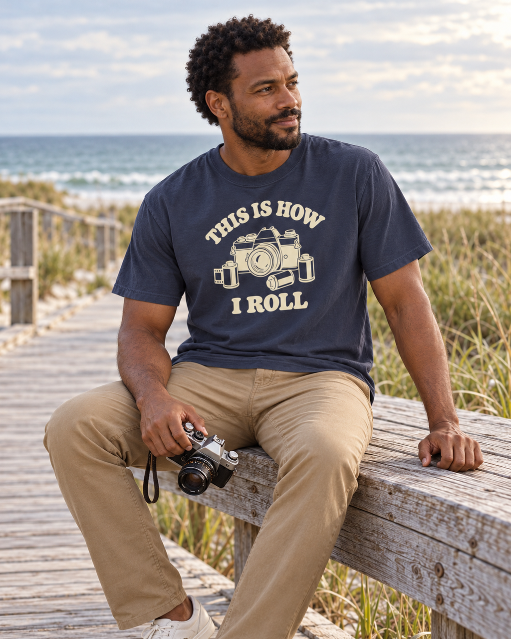This Is How I Roll Tee — Navy — lifestyle boardwalk rest with a vintage camera