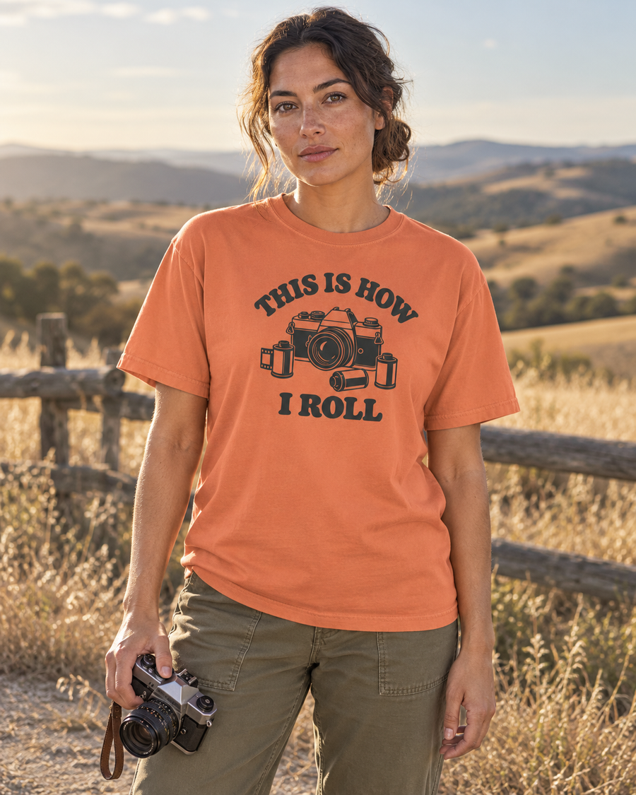 This Is How I Roll Tee — Terracotta — lifestyle hillside portrait holding a vintage 35mm camera
